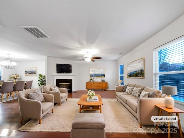 living room featuring dark hardwood / wood-style flooring and ceiling fan with notable chandelier