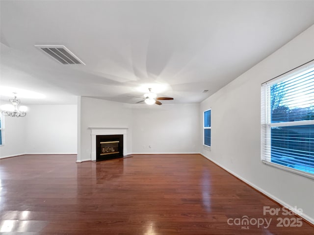 unfurnished living room featuring dark hardwood / wood-style floors and ceiling fan with notable chandelier