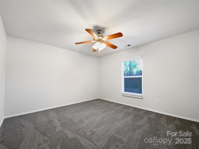 empty room with ceiling fan and dark colored carpet