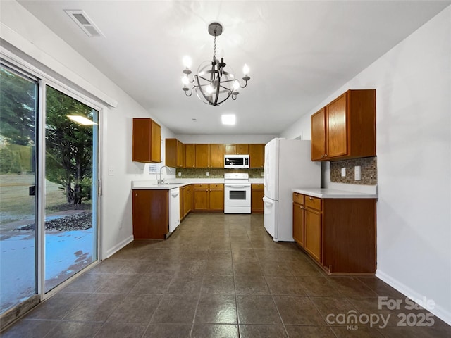 kitchen with pendant lighting, sink, white appliances, tasteful backsplash, and a chandelier