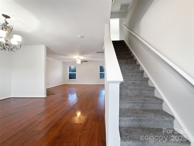 stairway with hardwood / wood-style flooring and ceiling fan with notable chandelier