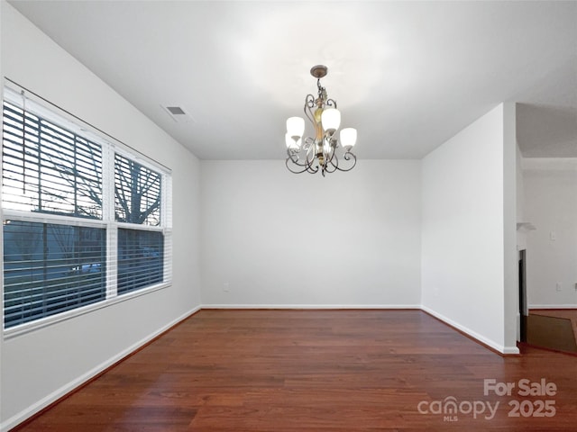 empty room featuring a notable chandelier and dark hardwood / wood-style floors