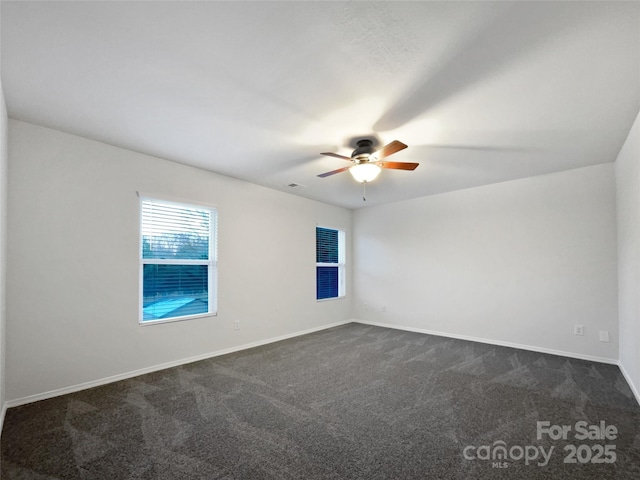 spare room with ceiling fan and dark colored carpet