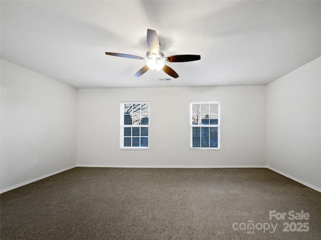 spare room featuring ceiling fan and dark colored carpet