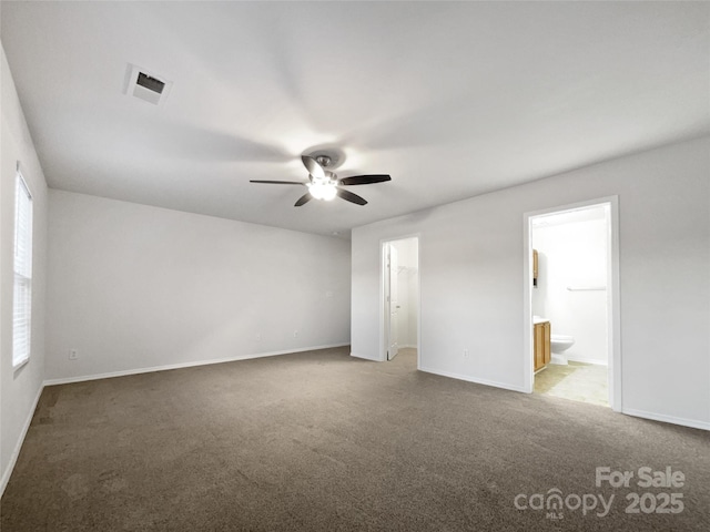 interior space with multiple windows, ensuite bathroom, carpet, and ceiling fan