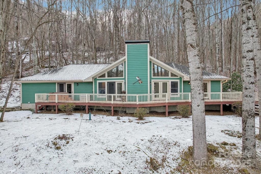 snow covered rear of property featuring a wooden deck