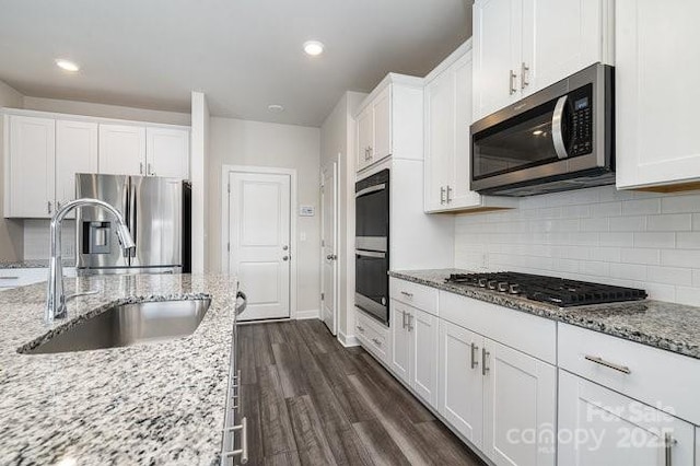 kitchen with sink, stainless steel appliances, white cabinets, and light stone countertops