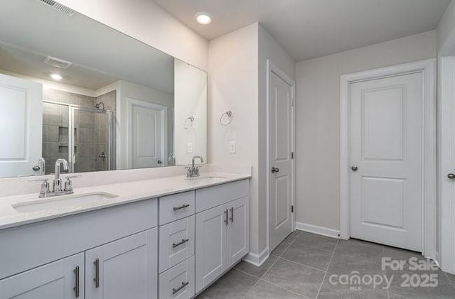 bathroom featuring a shower with door, vanity, and tile patterned floors