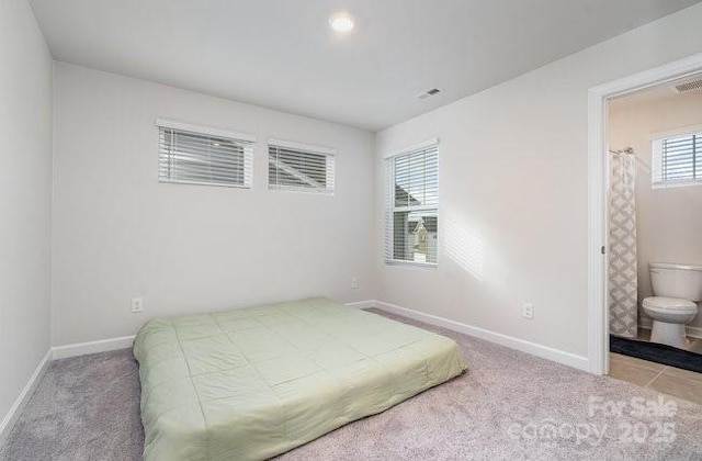 bedroom featuring ensuite bath and light colored carpet