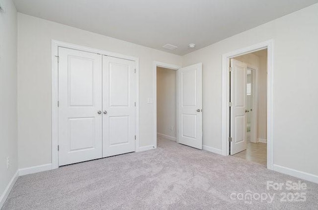 unfurnished bedroom featuring light colored carpet and a closet