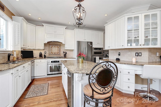 kitchen with stainless steel appliances, white cabinetry, sink, and decorative light fixtures