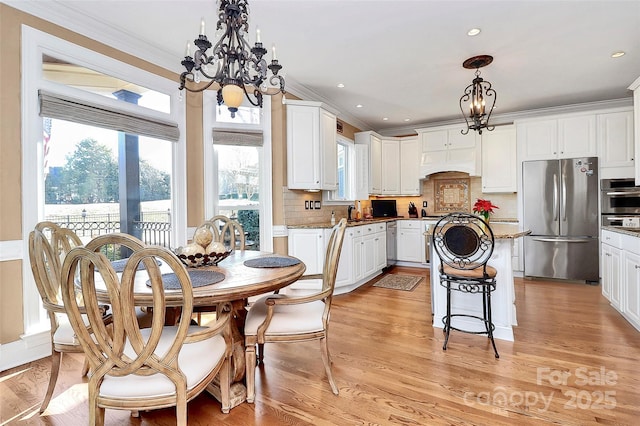 dining room with crown molding, sink, light wood-type flooring, and a notable chandelier