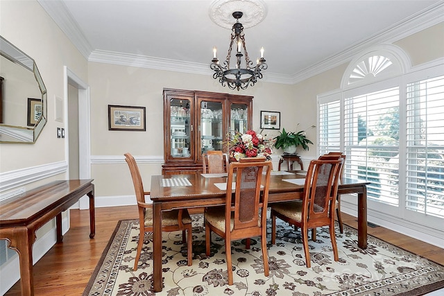 dining space with crown molding, hardwood / wood-style flooring, and a chandelier