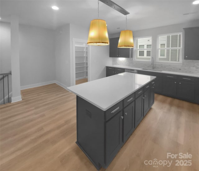 kitchen featuring sink, decorative light fixtures, light wood-type flooring, tasteful backsplash, and a kitchen island