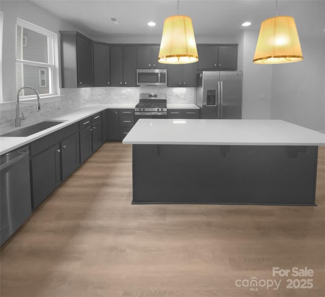 kitchen featuring sink, pendant lighting, stainless steel appliances, and a kitchen island