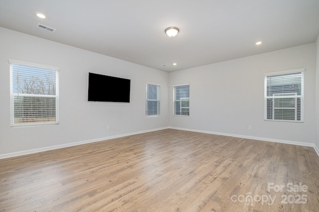 spare room with a wealth of natural light and light hardwood / wood-style floors