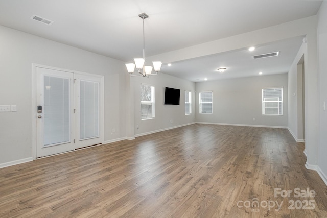 unfurnished room with hardwood / wood-style floors and a notable chandelier