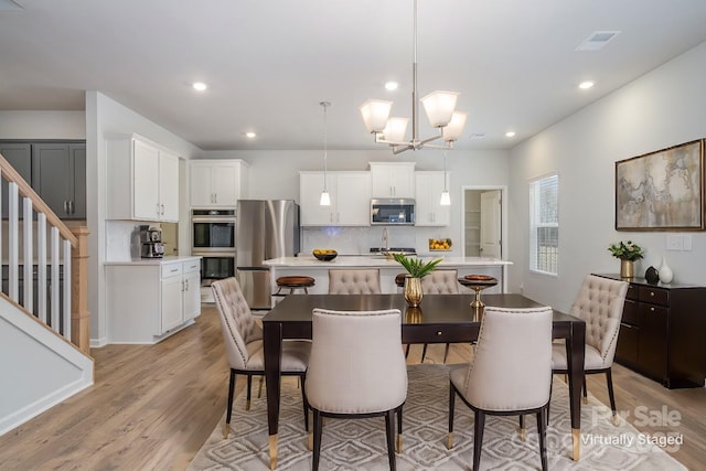 dining space featuring sink, an inviting chandelier, and light hardwood / wood-style flooring