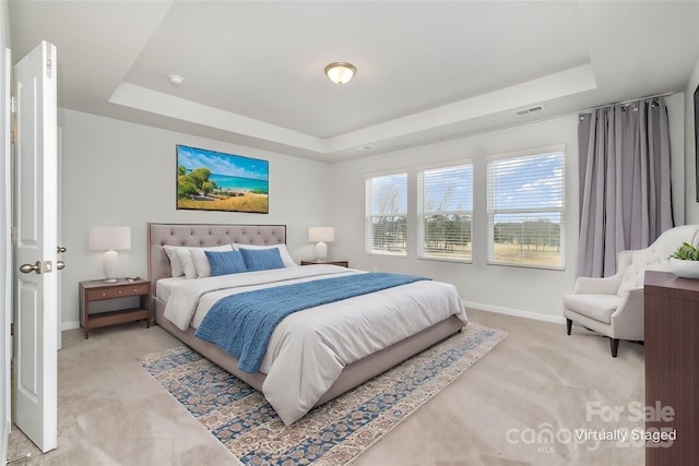 bedroom with light colored carpet and a raised ceiling