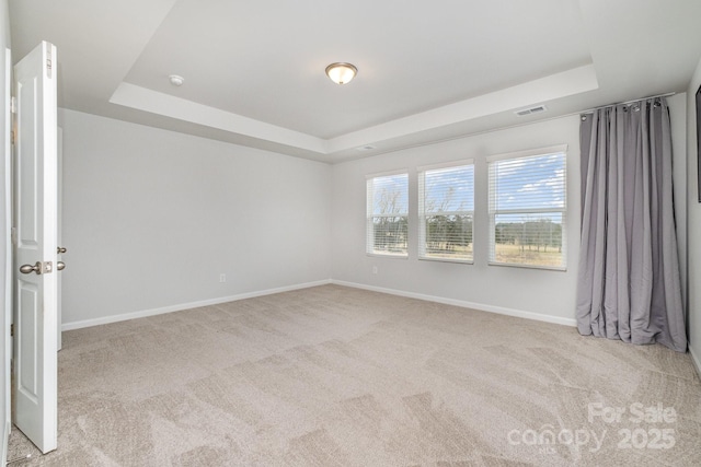 unfurnished room with a tray ceiling and light colored carpet