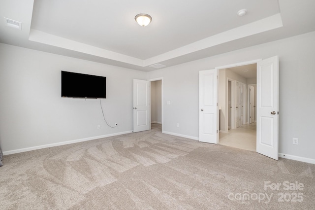 carpeted empty room with a raised ceiling