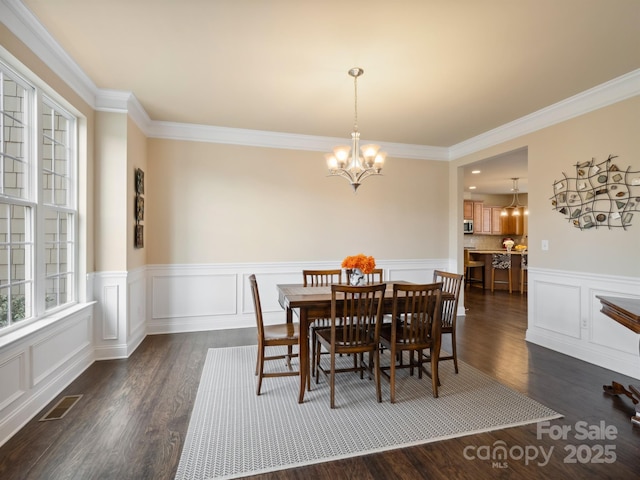 dining area with dark wood-style floors, crown molding, visible vents, and a notable chandelier