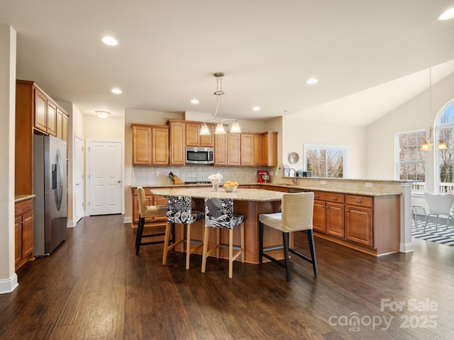 kitchen with tasteful backsplash, appliances with stainless steel finishes, dark wood-type flooring, a peninsula, and an inviting chandelier