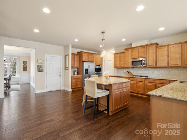 kitchen with tasteful backsplash, appliances with stainless steel finishes, light stone counters, and a center island