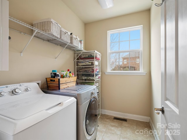 washroom with laundry area, baseboards, visible vents, washing machine and clothes dryer, and light tile patterned flooring