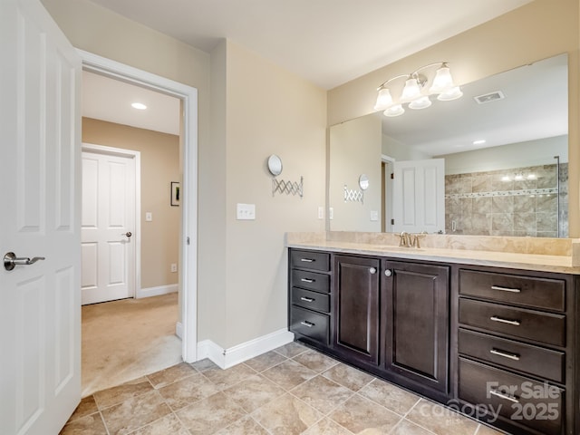 full bath with visible vents, vanity, tiled shower, baseboards, and tile patterned floors