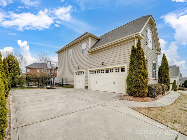 view of side of home with a garage, concrete driveway, and fence