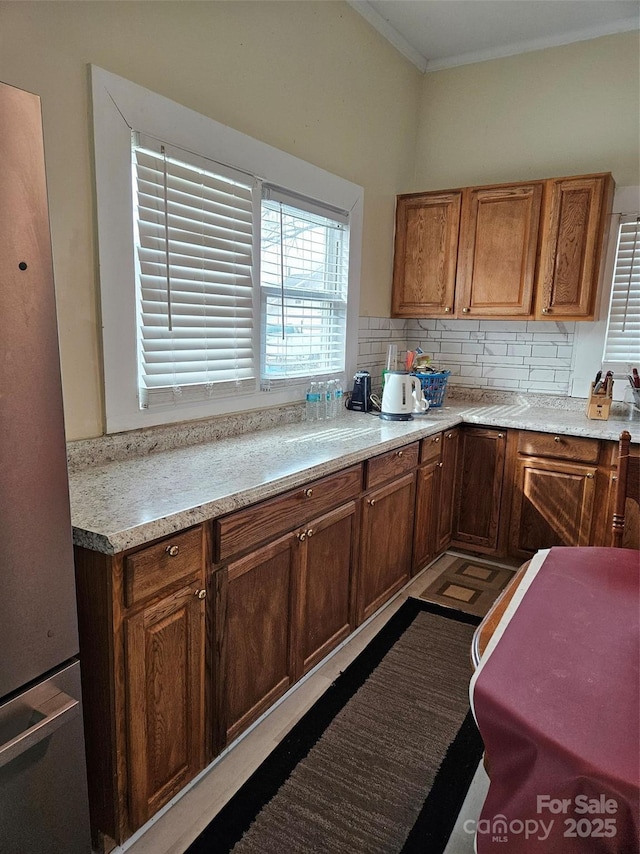 kitchen with stainless steel refrigerator, crown molding, and backsplash