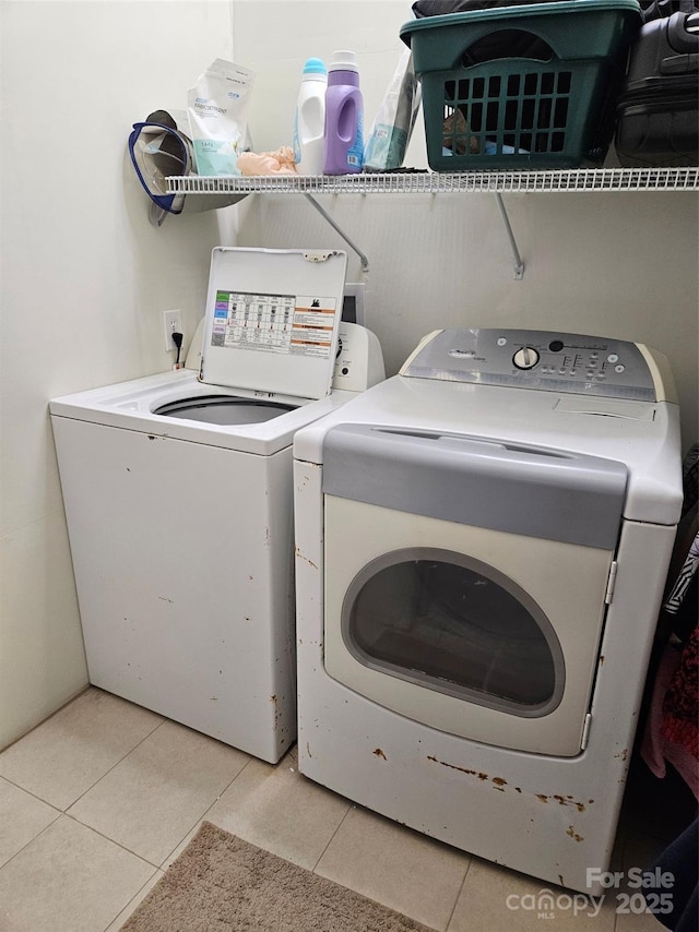 laundry area with independent washer and dryer and light tile patterned floors