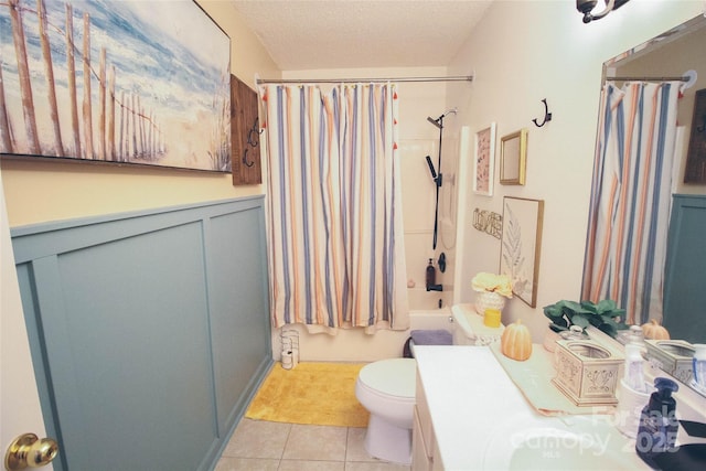 full bathroom with tile patterned flooring, a textured ceiling, toilet, vanity, and shower / bath combo with shower curtain