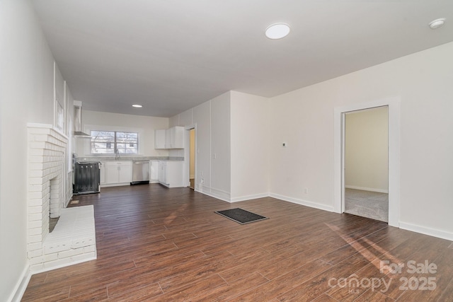 unfurnished living room featuring dark wood-type flooring and baseboards