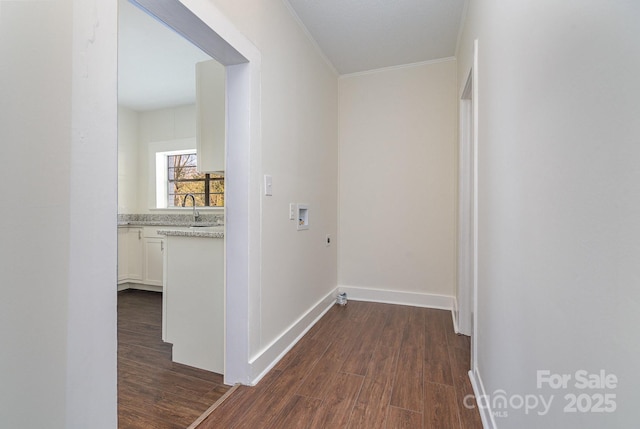 corridor featuring baseboards, dark wood finished floors, a sink, and ornamental molding