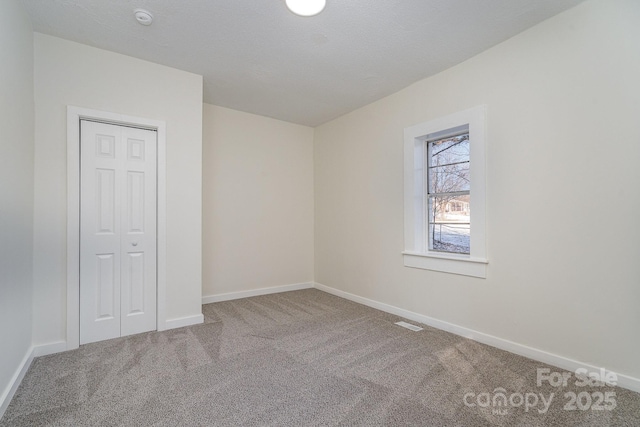 unfurnished bedroom featuring carpet floors, a closet, visible vents, a textured ceiling, and baseboards