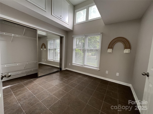 unfurnished bedroom featuring dark tile patterned floors and a closet