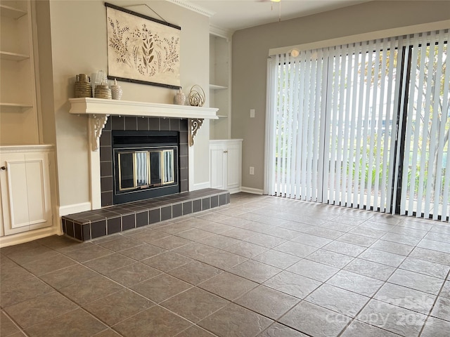 unfurnished living room featuring built in features, a tiled fireplace, and tile patterned floors