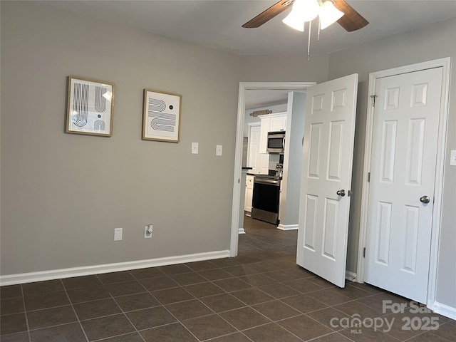 empty room featuring ceiling fan and dark tile patterned floors