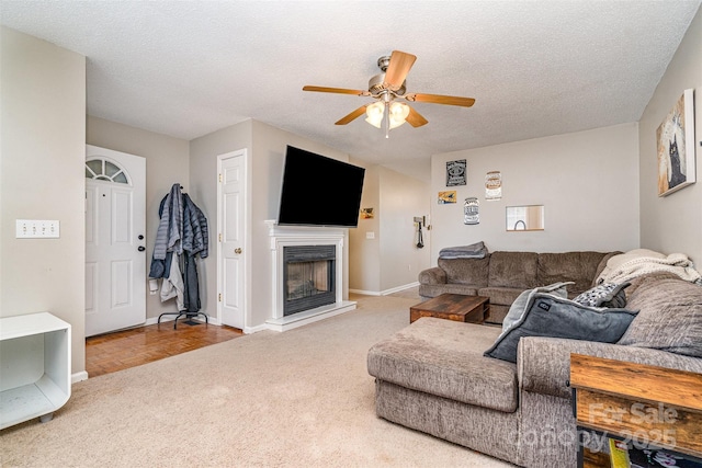 living room with ceiling fan, carpet flooring, and a textured ceiling