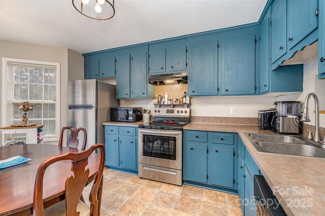 kitchen with appliances with stainless steel finishes, blue cabinets, sink, and a textured ceiling