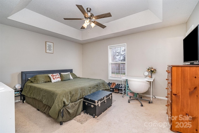 carpeted bedroom with a tray ceiling, a textured ceiling, and ceiling fan