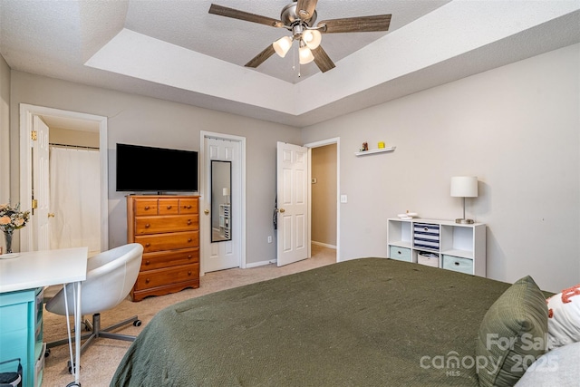 bedroom with light colored carpet, ceiling fan, and a tray ceiling