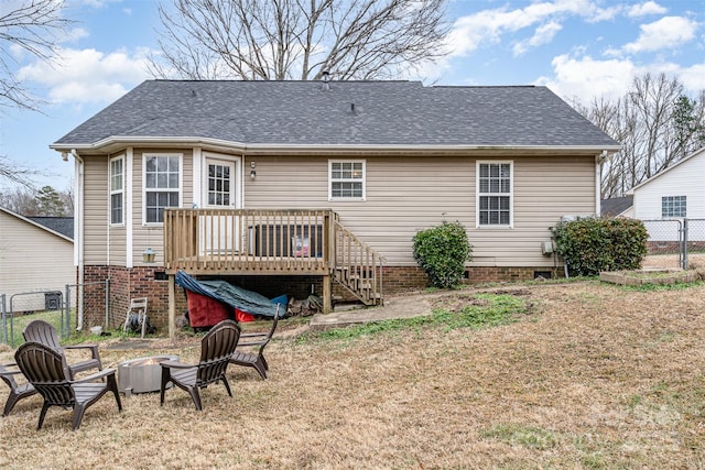 back of property with a wooden deck, a yard, and an outdoor fire pit