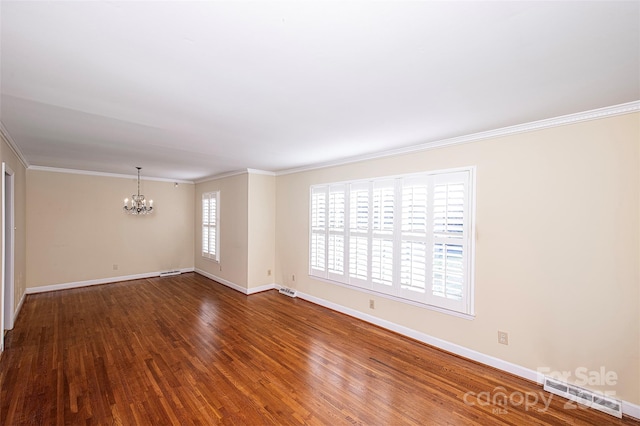 spare room featuring an inviting chandelier, crown molding, and hardwood / wood-style flooring