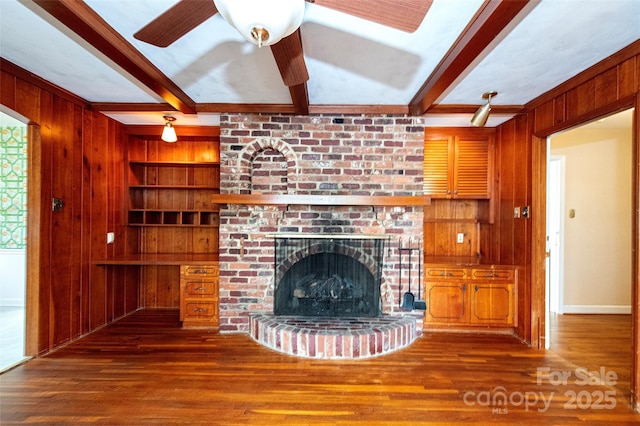 unfurnished living room with beamed ceiling, wooden walls, and a brick fireplace