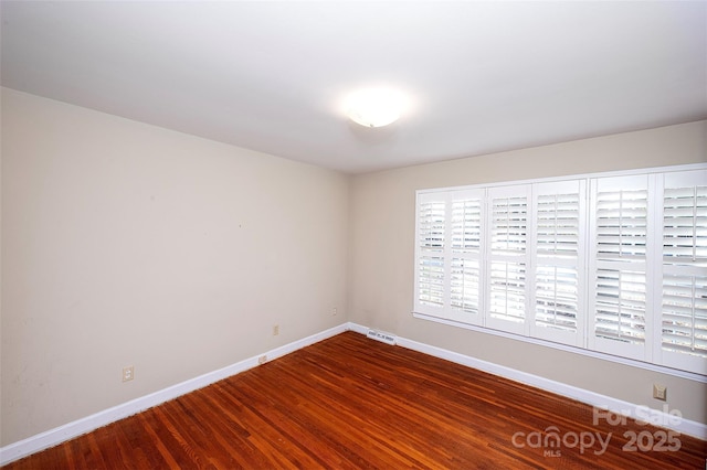 empty room with dark hardwood / wood-style flooring