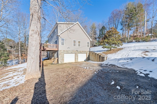 view of snowy exterior with a garage and a wooden deck