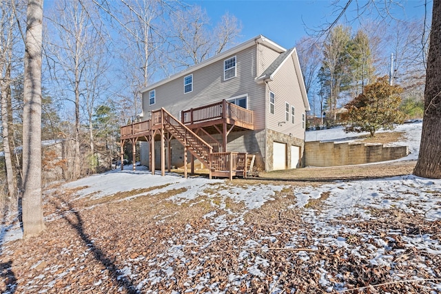 snow covered rear of property with a garage and a deck